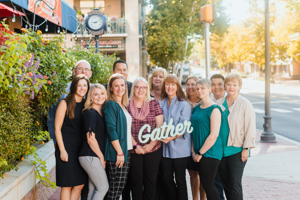 team members holding sign that says gather