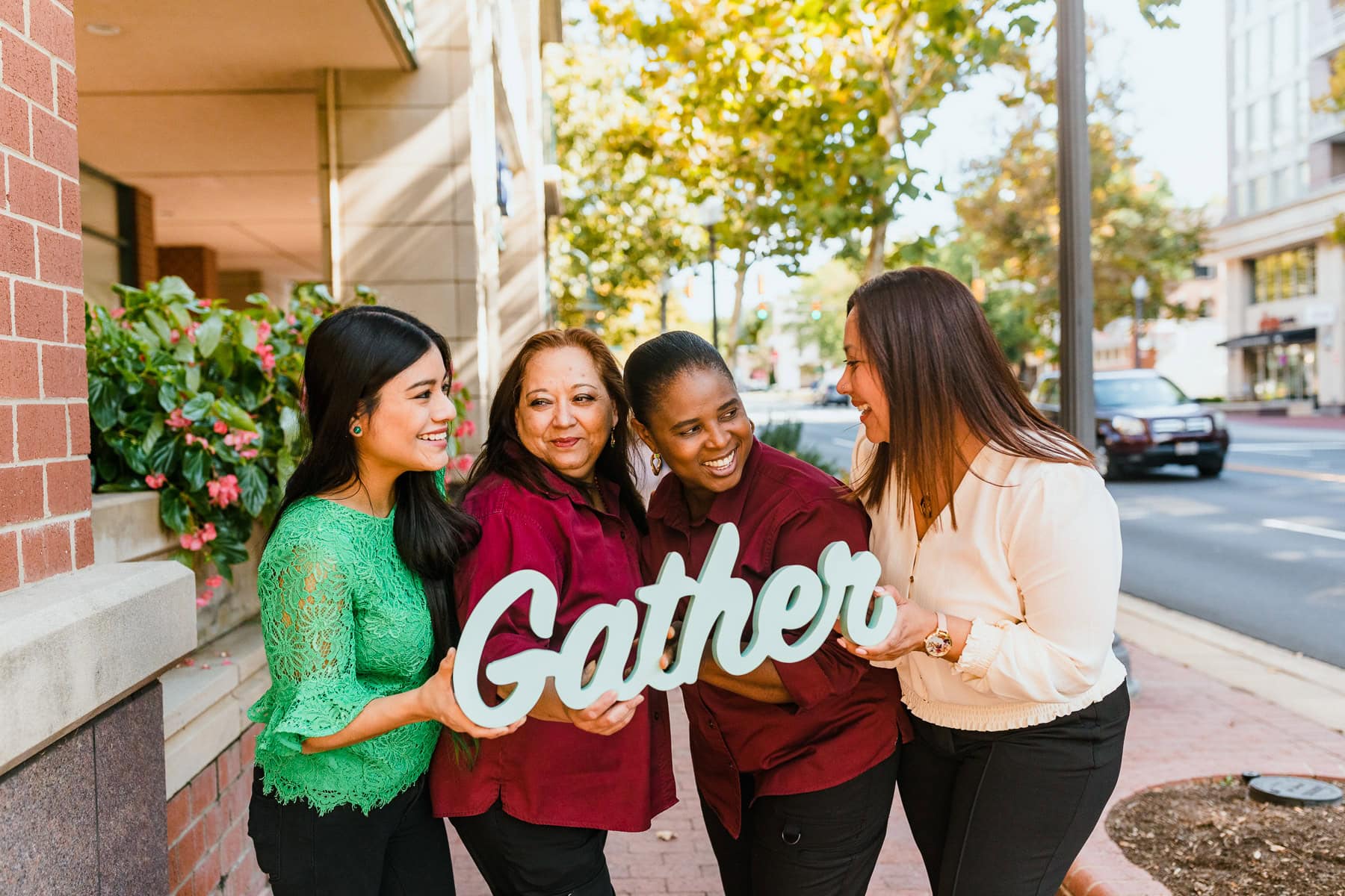 team members holding sign that says gather