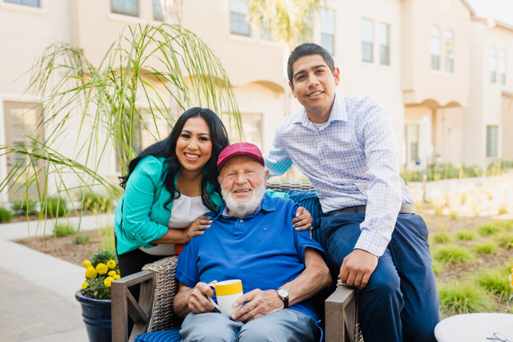 old man sitting with a younger man and woman for a photo