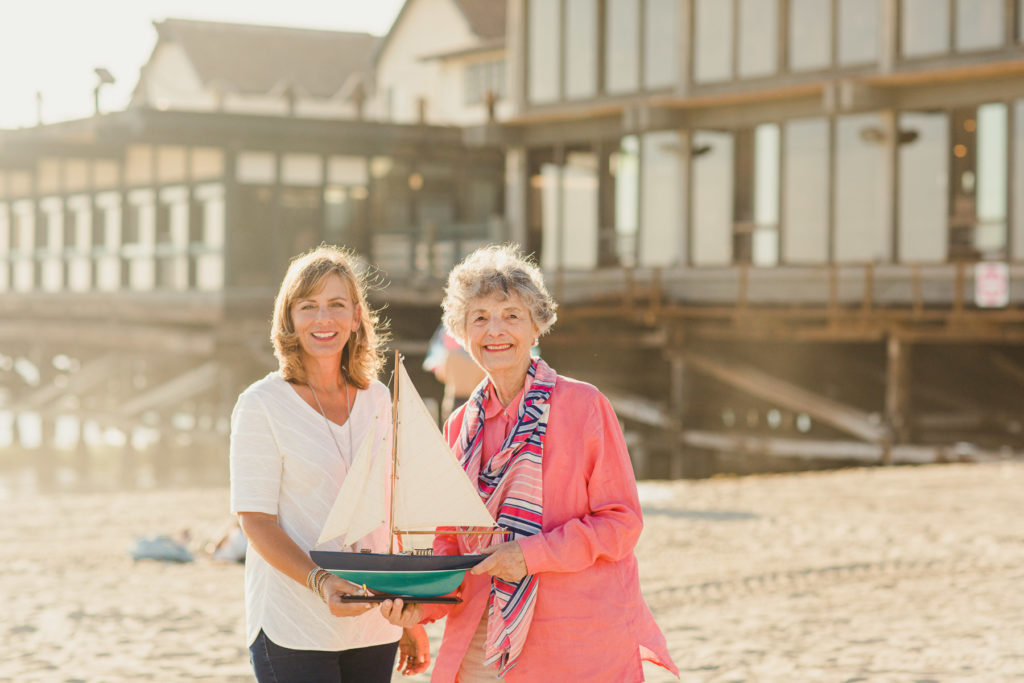 resident and caregiver at the beach holding a model boat