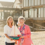 resident and caregiver at the beach holding a model boat