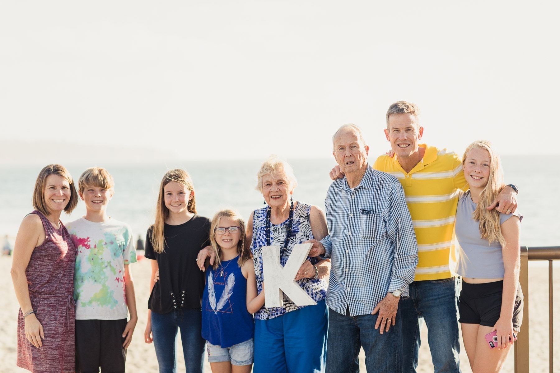 intergenerational family on the beach holding a K sign