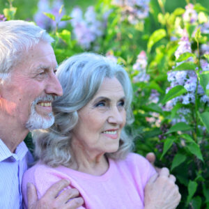 Portrait of beautiful senior couple by lilacs in the park.