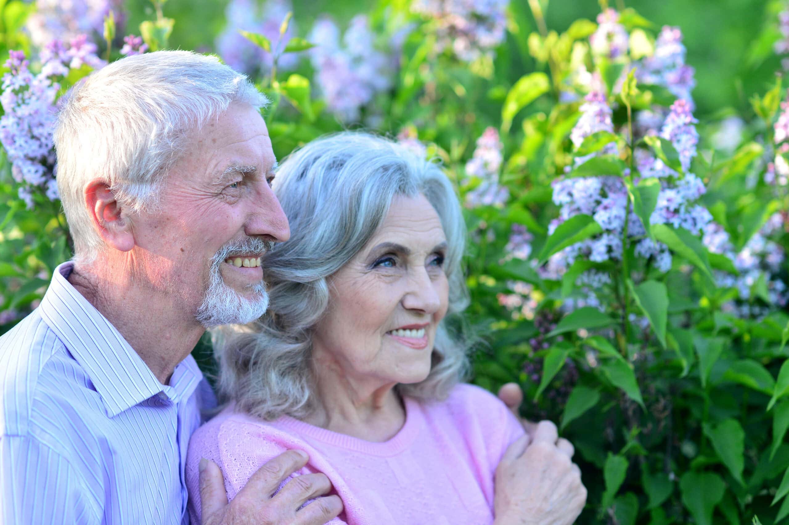 Portrait of beautiful senior couple by lilacs in the park.